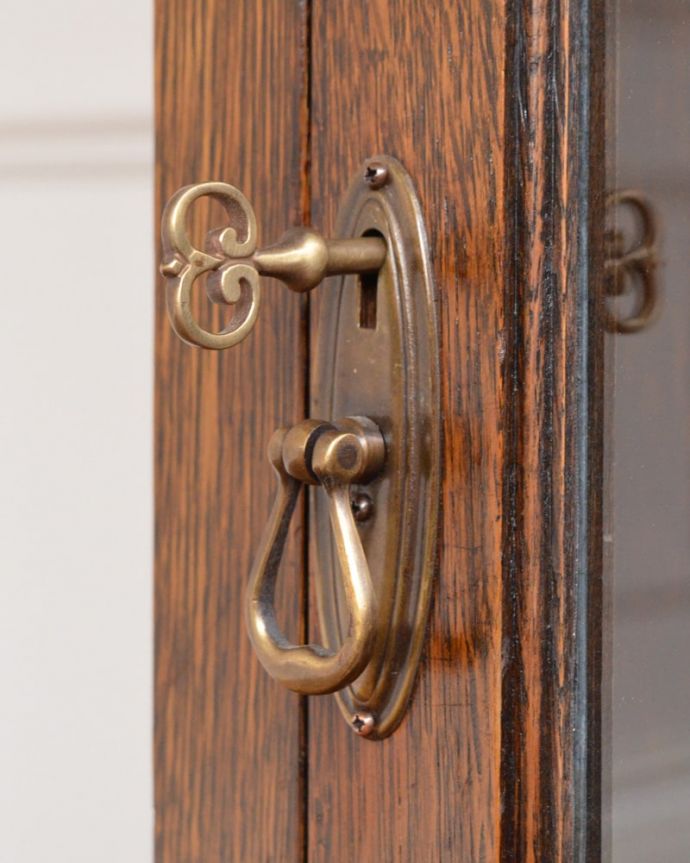 アンティークのキャビネット　アンティーク家具　英国から届いたアンティーク家具、ガラス扉のデザインが美しい木製のブックケース（本棚） 。大切なものも収納出来ますおとぎ話に出てくるような可愛いアンティークの鍵が付いています。(q-2081-f)