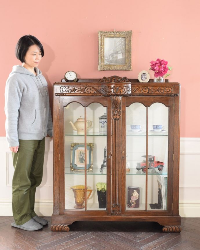 アンティークのキャビネット アンティーク家具 英国のアンティーク家具、お花の彫刻が華やかなアンティークのチャイナキャビネット。英国らしい堂々とした風格のあるガラスキャビネット重厚感ある佇まいで、落ち着いた雰囲気を演出してくれる英国のキャビネット。(q-2083-f)