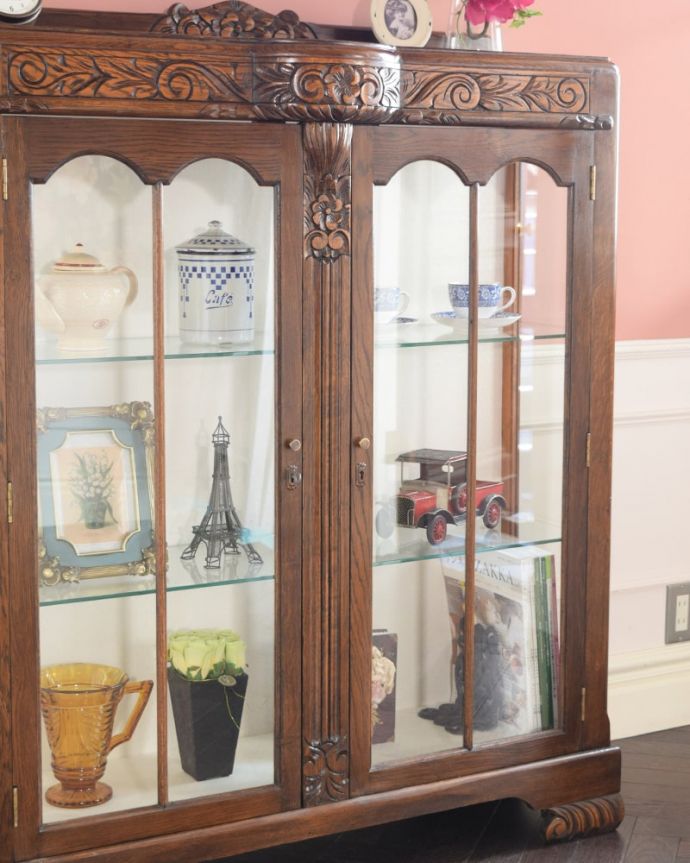 アンティークのキャビネット アンティーク家具 英国のアンティーク家具、お花の彫刻が華やかなアンティークのチャイナキャビネット。ガラス越しに中をのぞいてみると・・・アンティークのガラスを通して中に入っているものを見ると、なんだかちょっと高級に見えるんです。(q-2083-f)