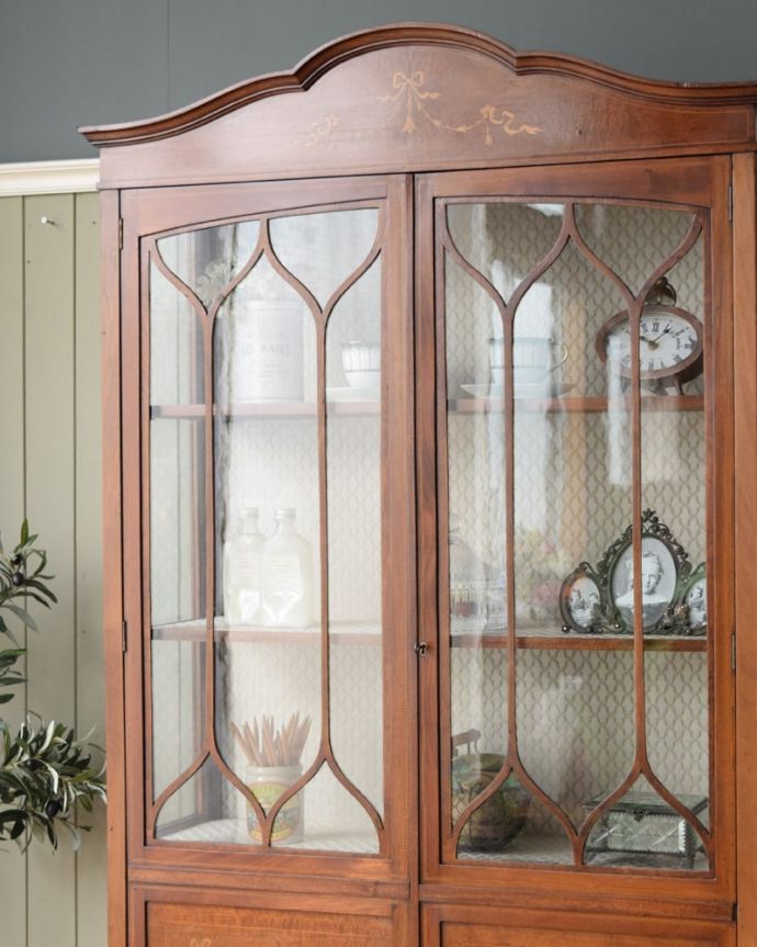 アンティークのキャビネット アンティーク家具 象嵌入りの美しい英国家具、マホガニー材が美しいアンティークのガラスキャビネット。扉に描かれた模様の美しさアンティークのガラスを通して中に入っているものを見ると、なんだかちょっと高級に見えるんです。(q-2106-f)