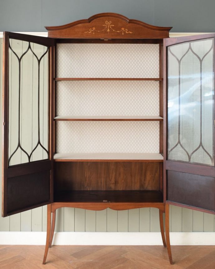 アンティークのキャビネット アンティーク家具 象嵌入りの美しい英国家具、マホガニー材が美しいアンティークのガラスキャビネット。扉を開けてみると・・・棚板と背板に貼ってあるクロスは修復の時、新しいものに張り替えました。(q-2106-f)