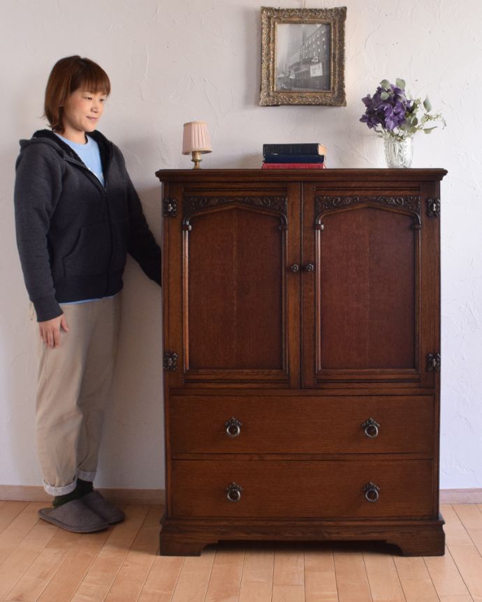 アンティークのチェスト アンティーク家具 葡萄の装飾が美しい、英国輸入のオーク材のカップボードチェスト(食器棚)。中が見えないので、生活感が出てしまう細々した物をたっぷり収納するのにピッタリです!(モデルの身長は157cmです)。(q-994-f)
