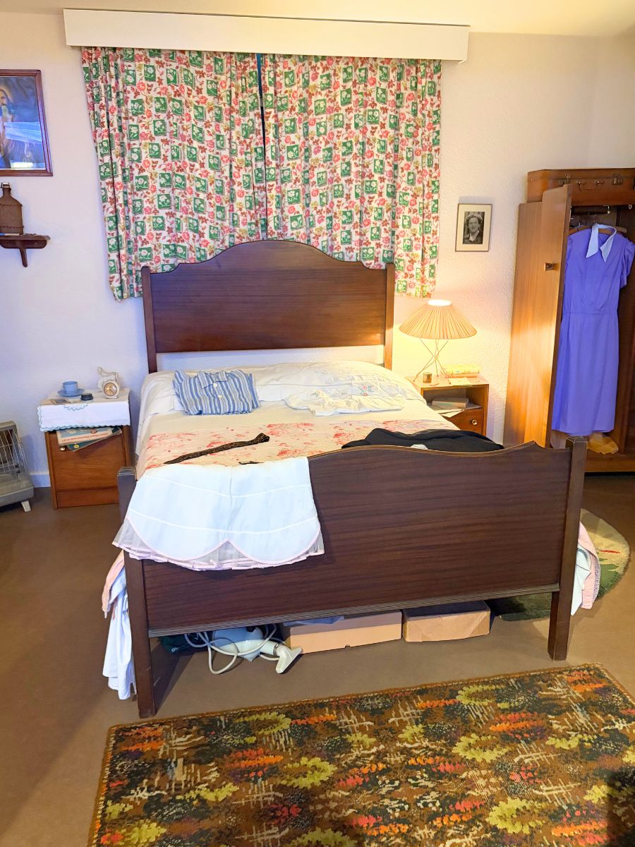 戦後の寝室インテリア。シンプルな木製ベッドとカーテン