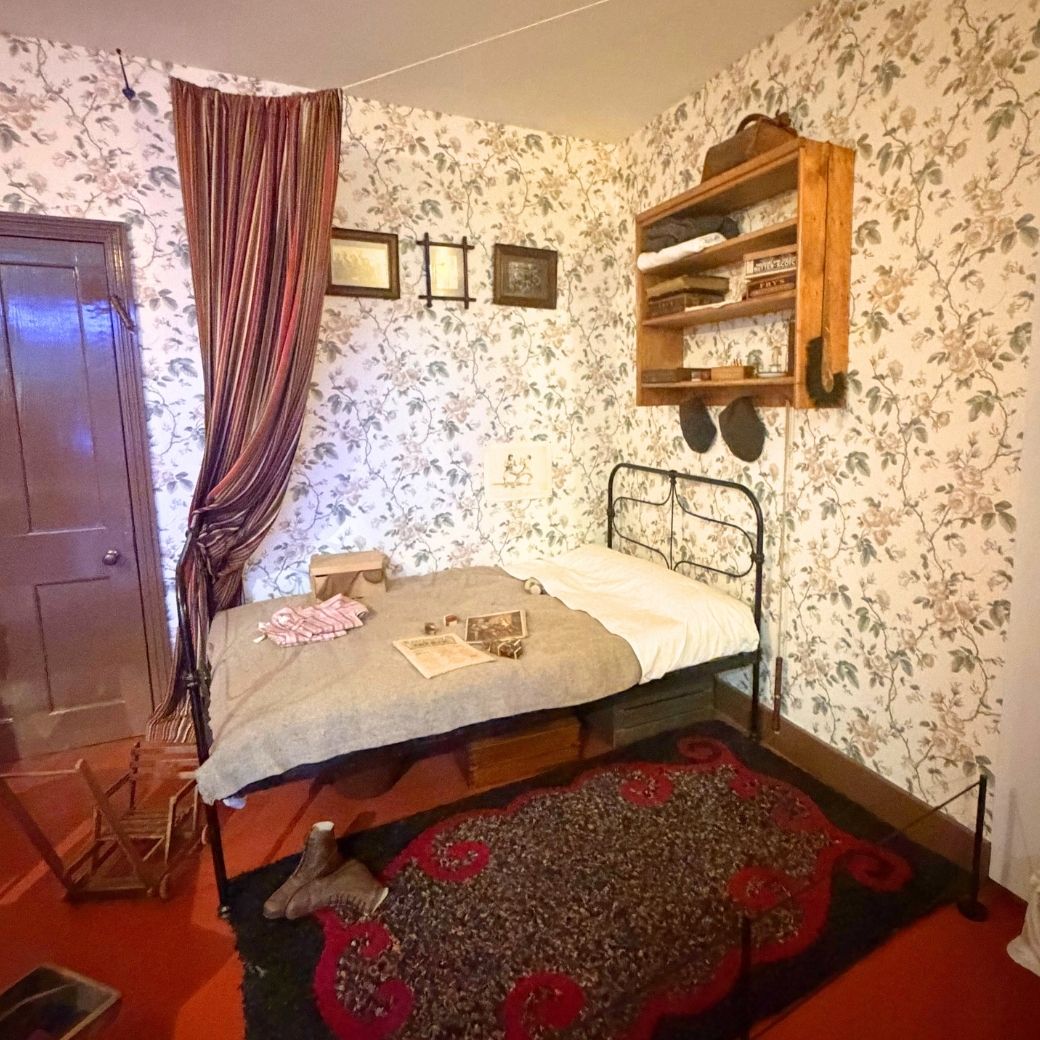 テネメントのシンプルな鉄製ベッドと質素なインテリア